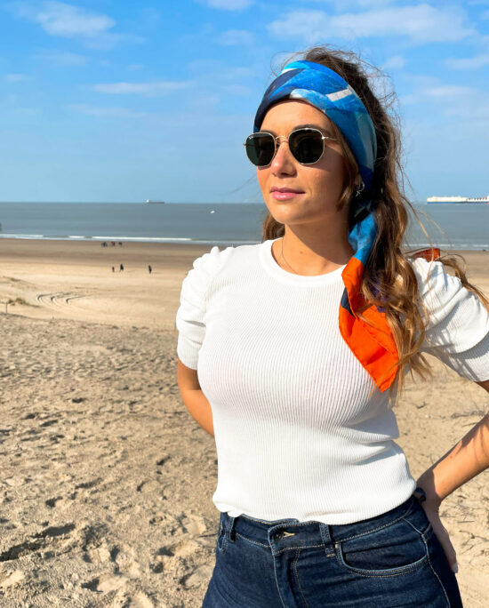 woman with a white top and a scarf on her head on the beach